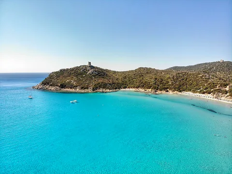 Baia turchese con torre spagnola sul promontorio